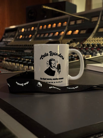 Arda Recorders branded black lanyard displayed with studio mug in analog recording studio
